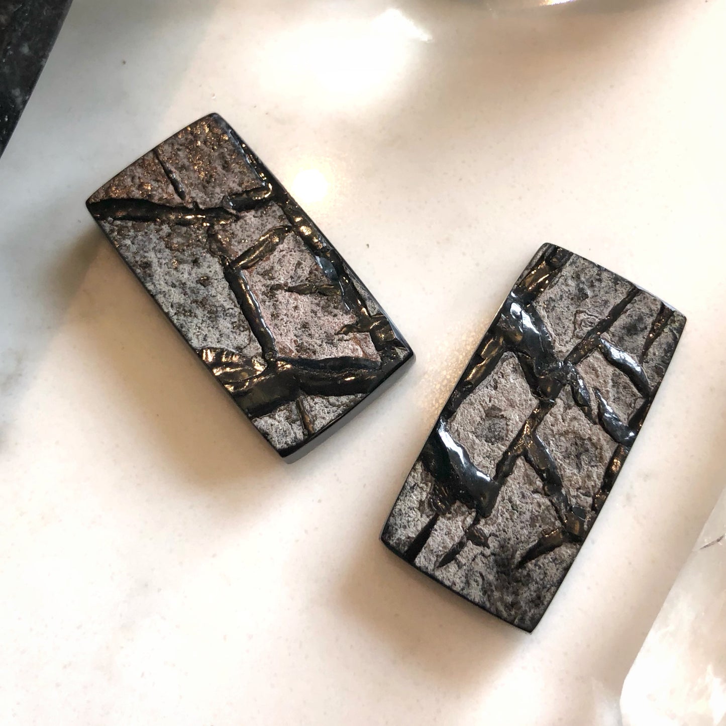 Pair of rectangular earrings with a stone-like pattern on a light background