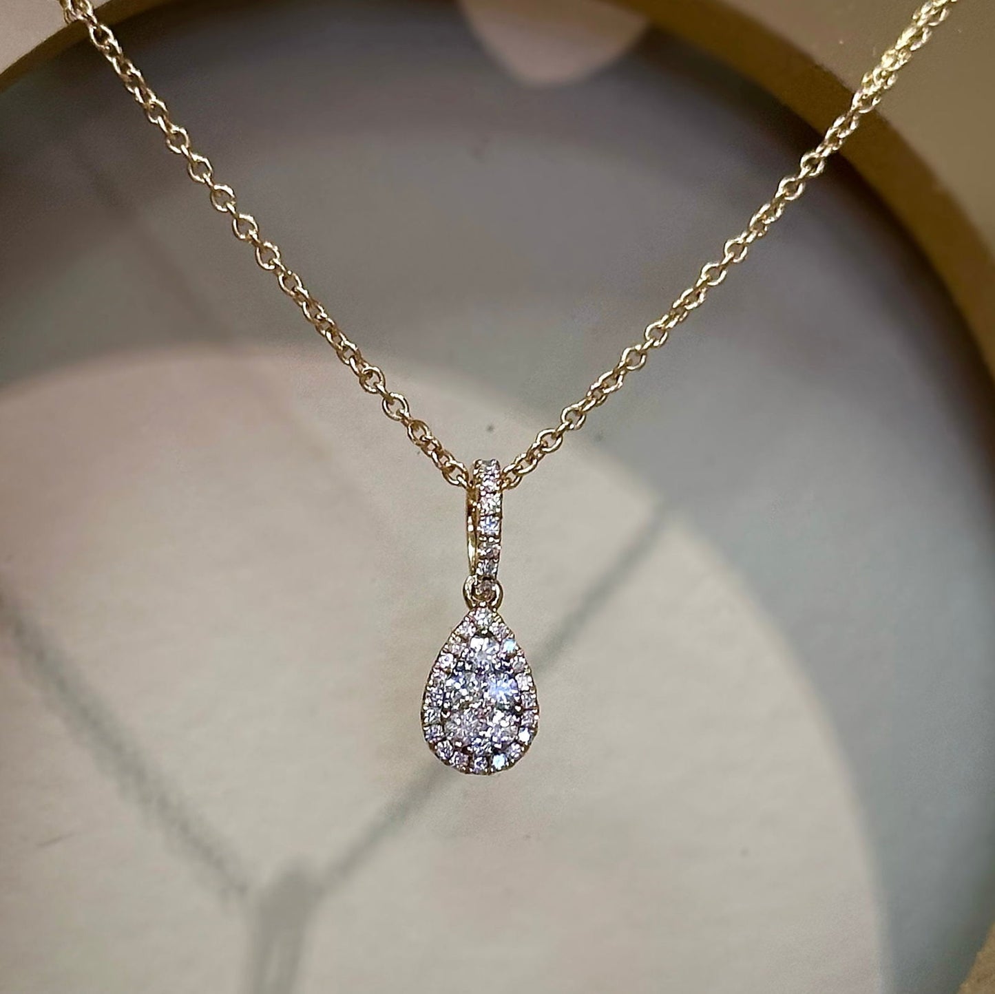 Photo of Halo Pear Diamond Pendant in a decorative scene, designed by , available at Plumb Gold & Plumb Silver