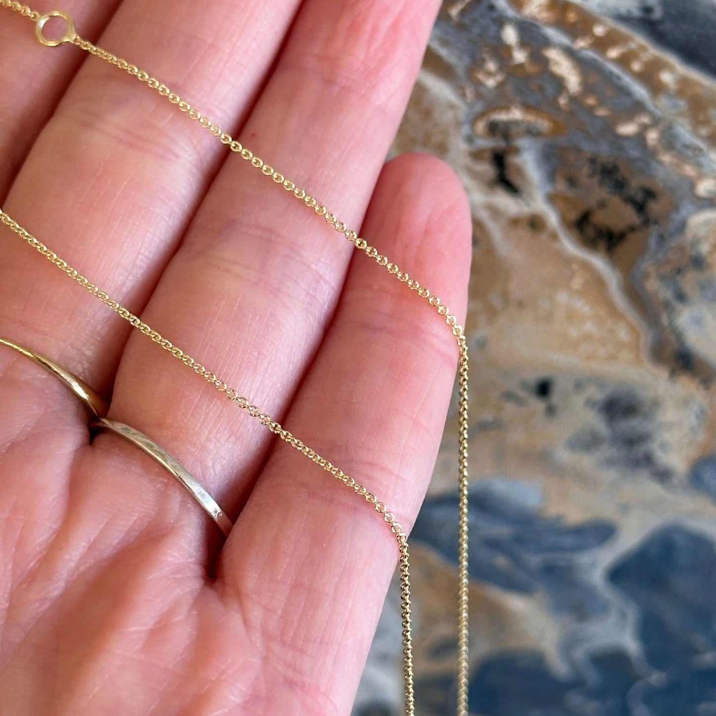 Photo of Adjustable Length Gold Cable Chain in a decorative scene, designed by -, available at Plumb Gold & Plumb Silver
