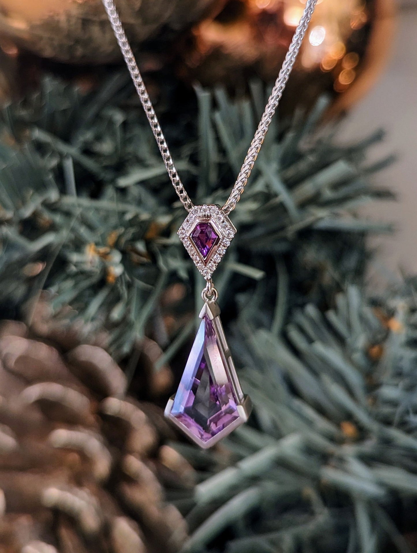 Photo of Amethyst and Pink Sapphire Pendant in a decorative scene, designed by , available at Plumb Gold & Plumb Silver