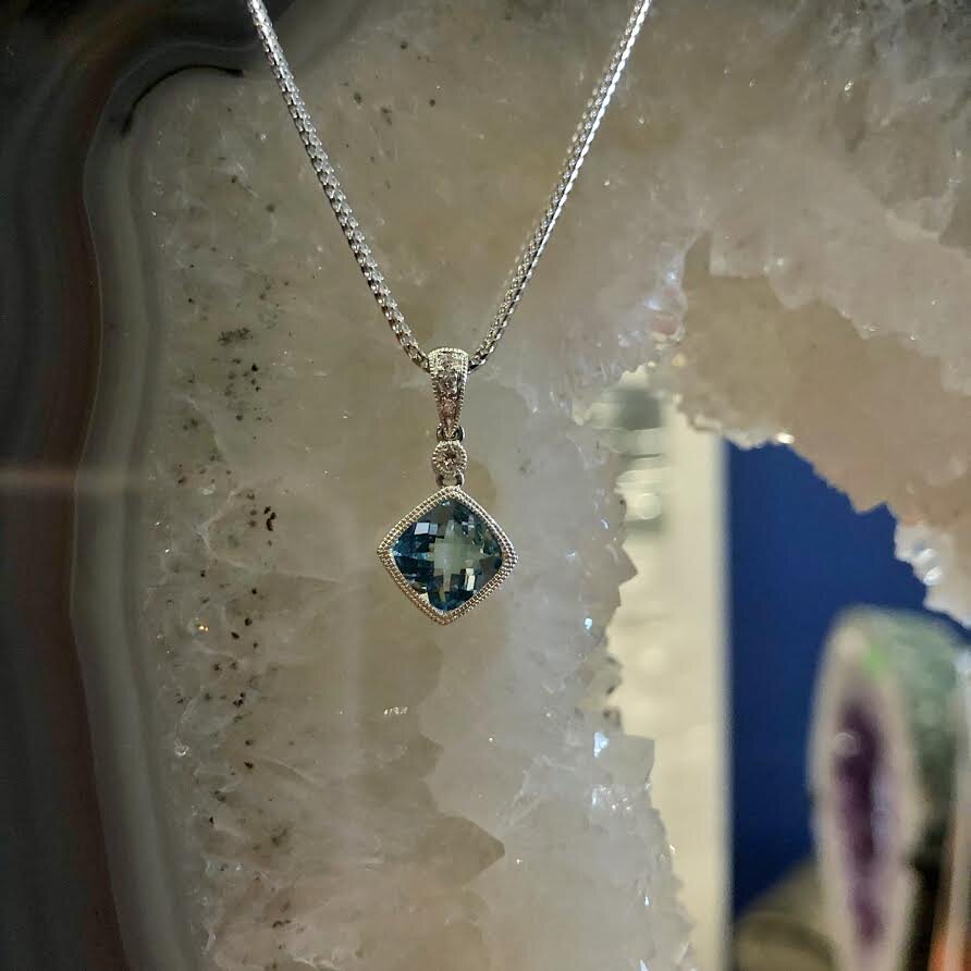 Photo of Aquamarine and Diamond Milgrain Pendant in a decorative scene, designed by , available at Plumb Gold & Plumb Silver