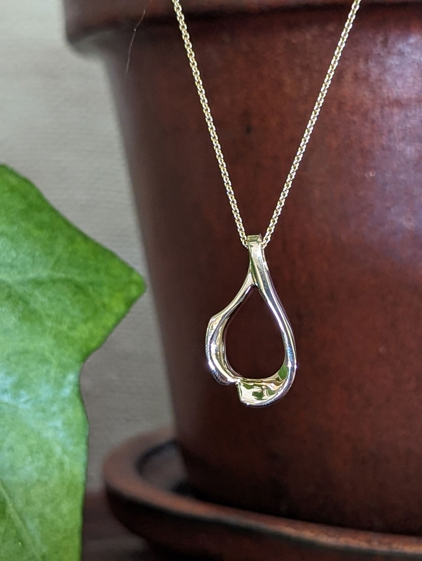 Photo of Asymmetric Loop Pendant in a decorative scene, designed by , available at Plumb Gold & Plumb Silver