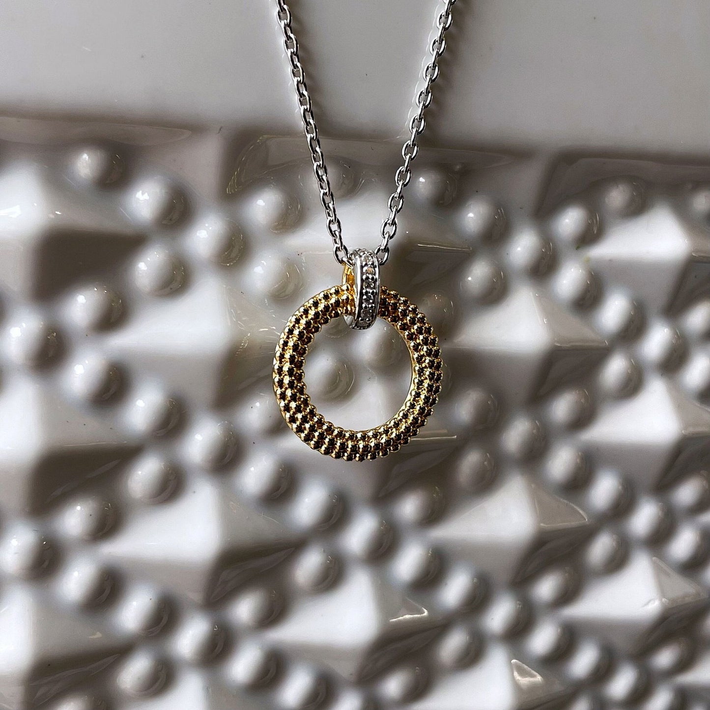 Photo of Beaded Circle Necklace in a decorative scene, designed by , available at Plumb Gold & Plumb Silver