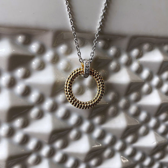 Photo of Beaded Circle Necklace in a decorative scene, designed by , available at Plumb Gold & Plumb Silver