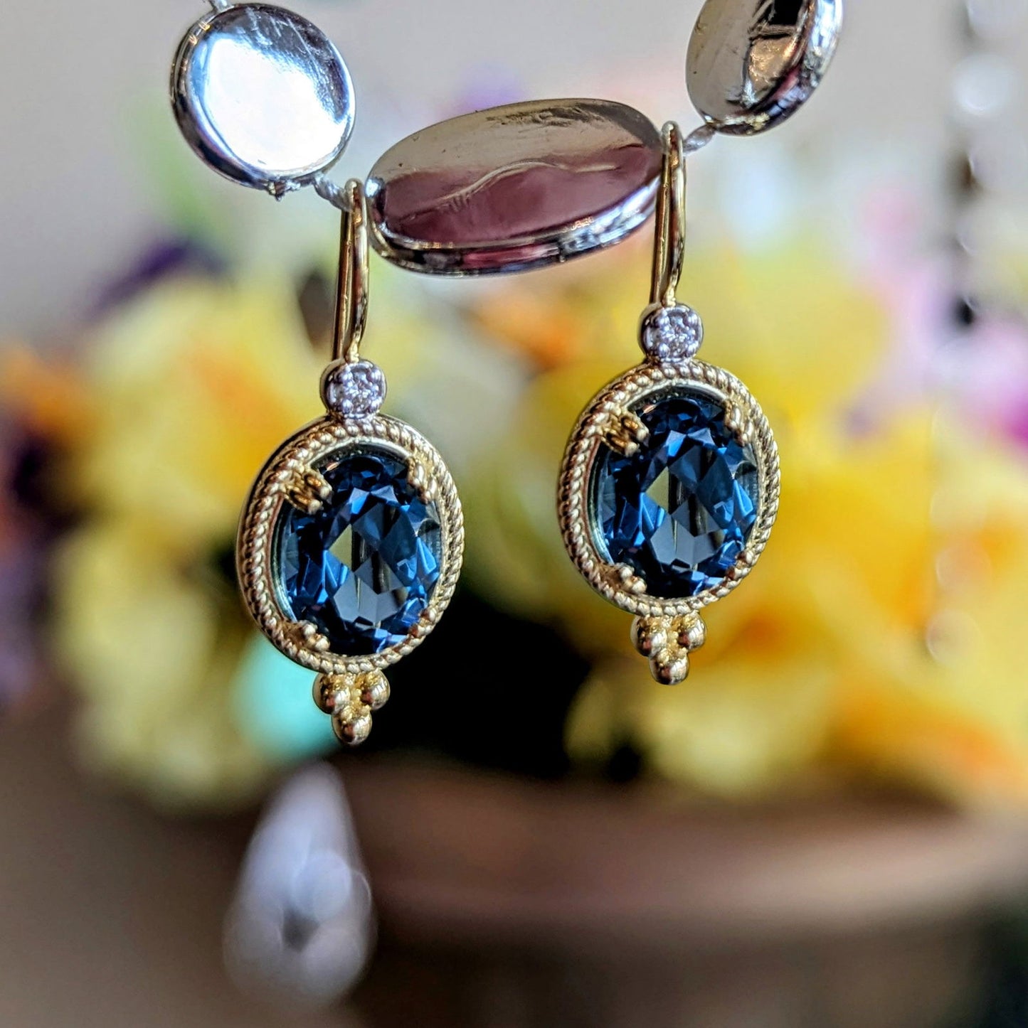 Photo of Beaded London Blue Topaz Drop Earrings in a decorative scene, designed by , available at Plumb Gold & Plumb Silver