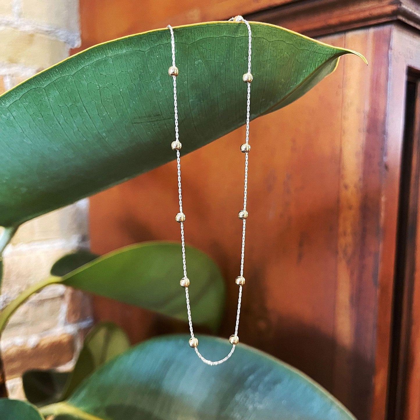 Photo of Beaded Station Chain in a decorative scene, designed by , available at Plumb Gold & Plumb Silver
