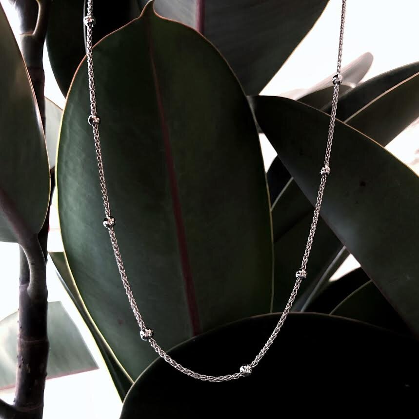 Photo of Beaded Wheat Necklace in a decorative scene, designed by , available at Plumb Gold & Plumb Silver