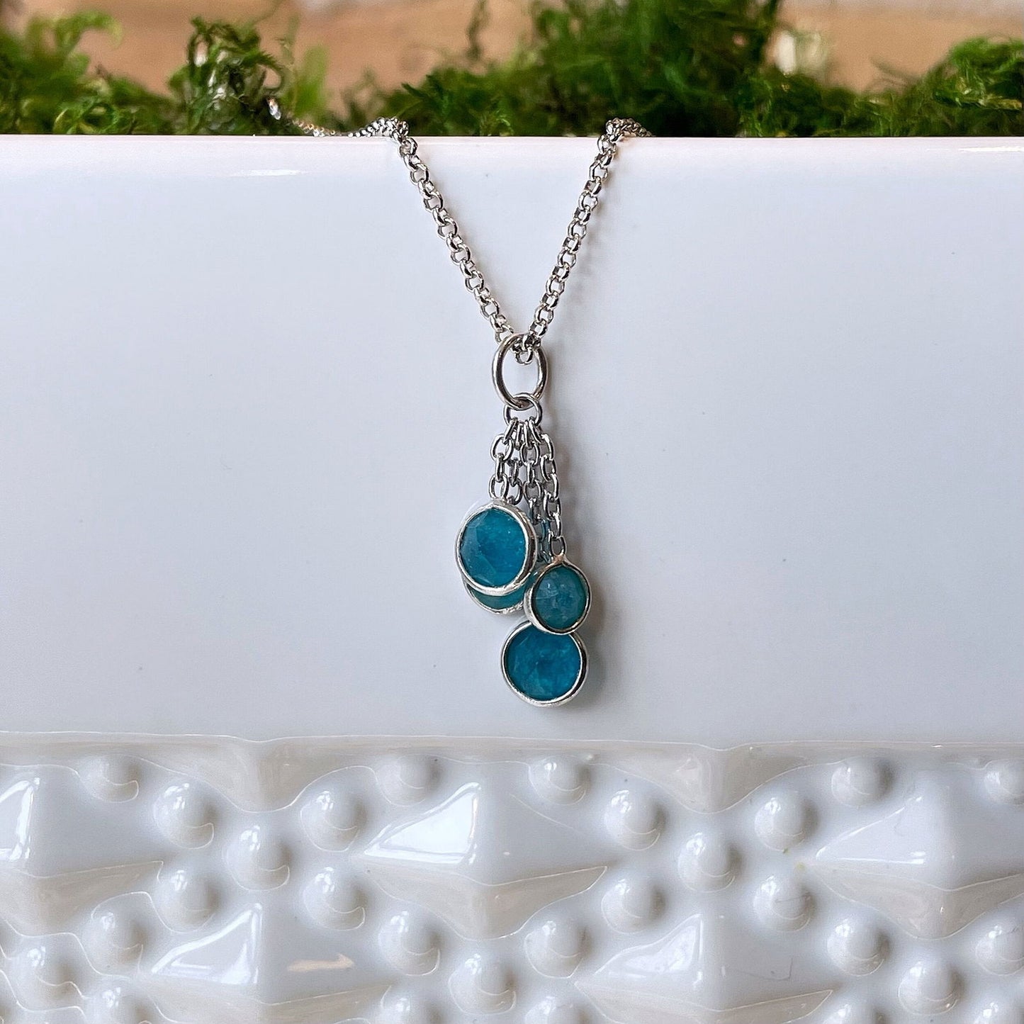 Photo of “Bella” Apatite Tassel Pendant in a decorative scene, designed by , available at Plumb Gold & Plumb Silver