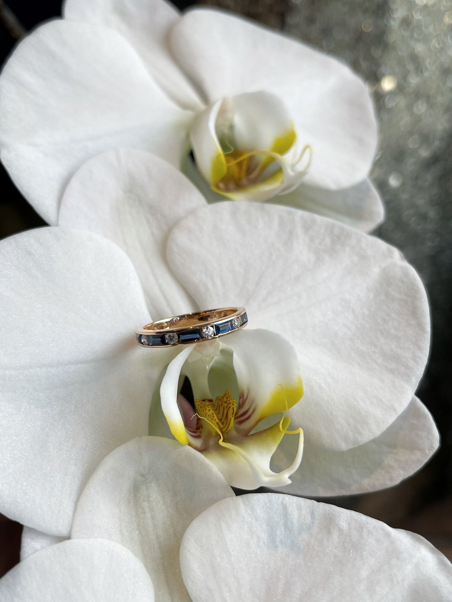 Photo of Blue Sapphire and Diamond Band in a decorative scene, designed by , available at Plumb Gold & Plumb Silver
