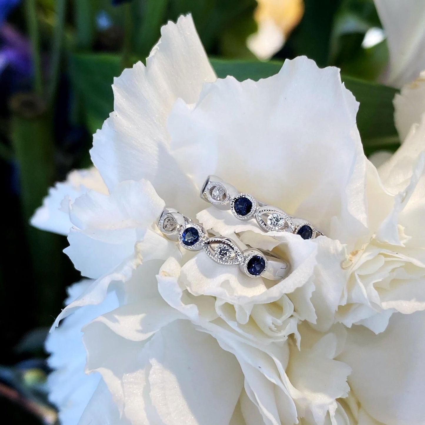 Photo of Blue Sapphire and Diamond Hoop Earrings in a decorative scene, designed by , available at Plumb Gold & Plumb Silver