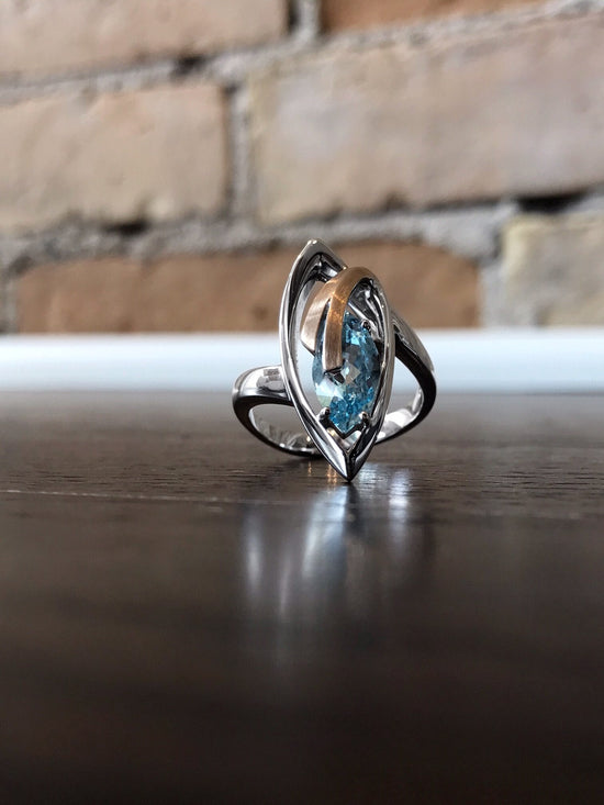 Photo of Blue Topaz Marquise Ring in a decorative scene, designed by , available at Plumb Gold & Plumb Silver