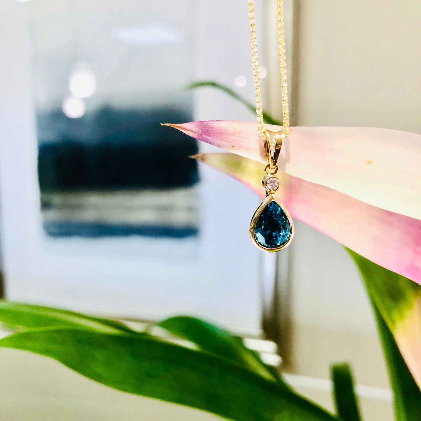Photo of Blue Zircon Diamond Drop Pendant in a decorative scene, designed by , available at Plumb Gold & Plumb Silver