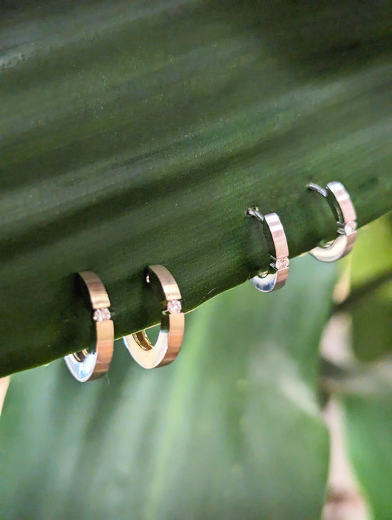 Photo of Breuning Matte Diamond Huggie Hoops in a decorative scene, designed by , available at Plumb Gold & Plumb Silver