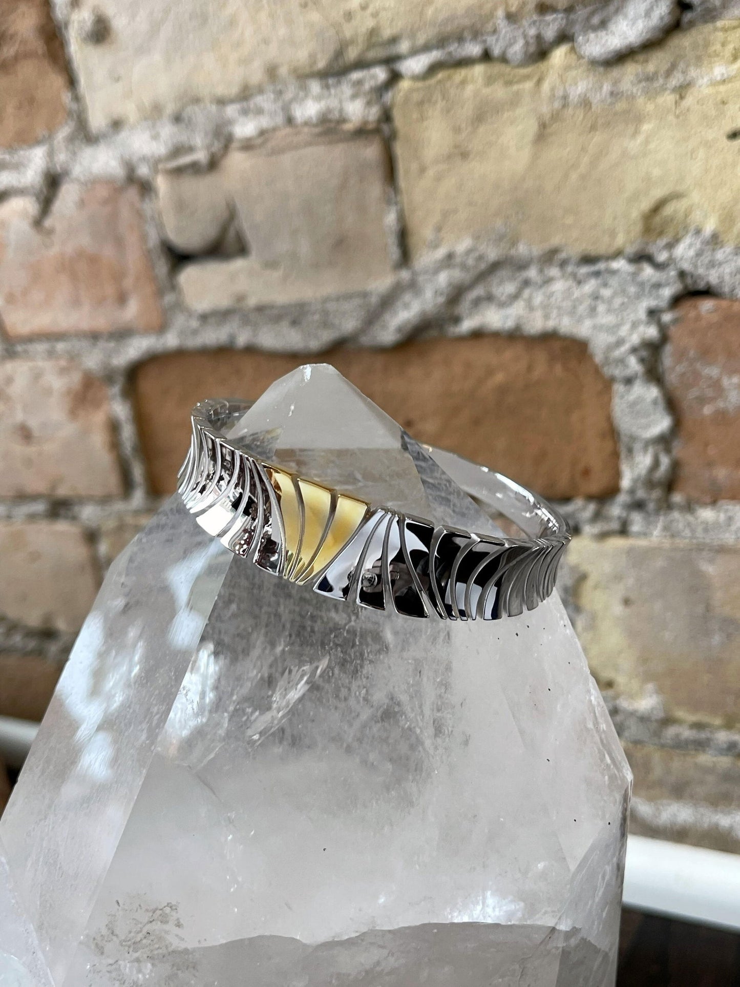 Photo of Breuning Two-Tone Zebra Bangle in a decorative scene, designed by , available at Plumb Gold & Plumb Silver