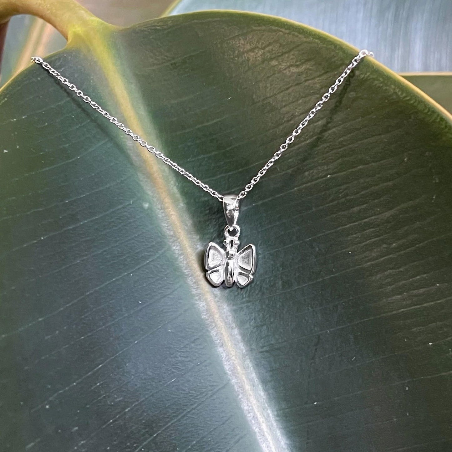 Photo of Butterfly Necklace in a decorative scene, designed by , available at Plumb Gold & Plumb Silver