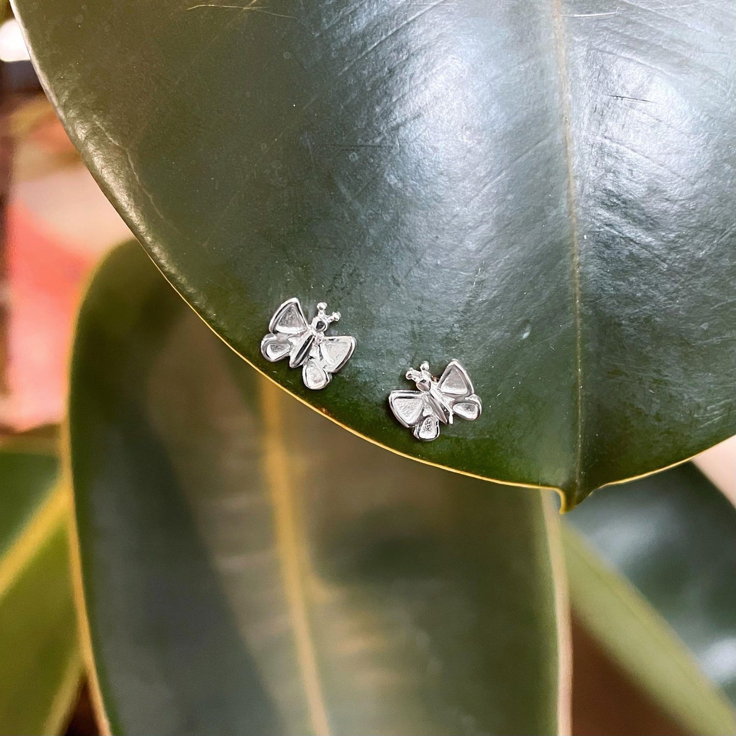 Photo of Butterfly Stud Earrings in a decorative scene, designed by , available at Plumb Gold & Plumb Silver