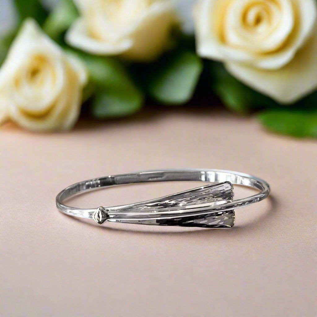 Photo of "Cascade" Bangle in a decorative scene, designed by , available at Plumb Gold & Plumb Silver