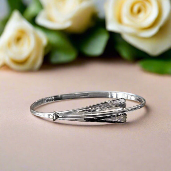 Photo of "Cascade" Bangle in a decorative scene, designed by , available at Plumb Gold & Plumb Silver