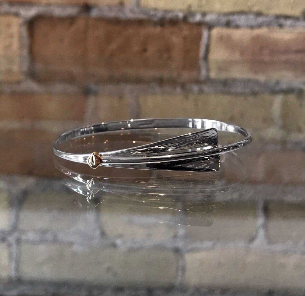 Photo of "Cascade" Bangle in a decorative scene, designed by , available at Plumb Gold & Plumb Silver