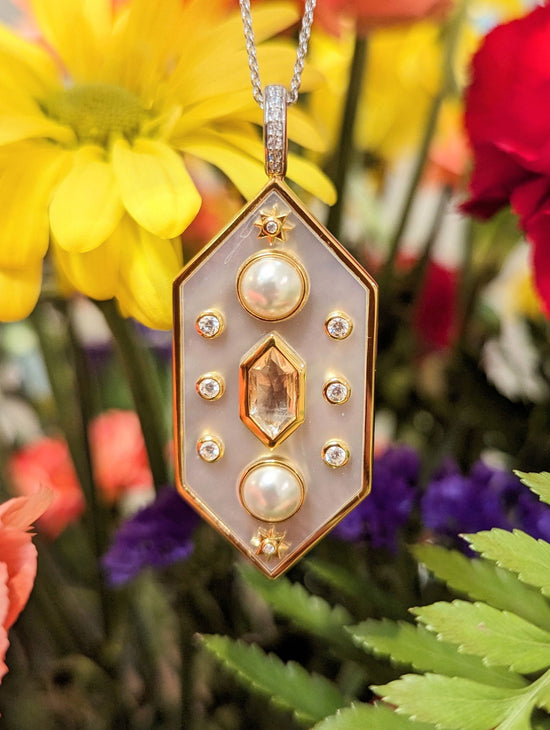Photo of Celestial Large Hexagon Mother of Pearl Pendant in a decorative scene, designed by , available at Plumb Gold & Plumb Silver