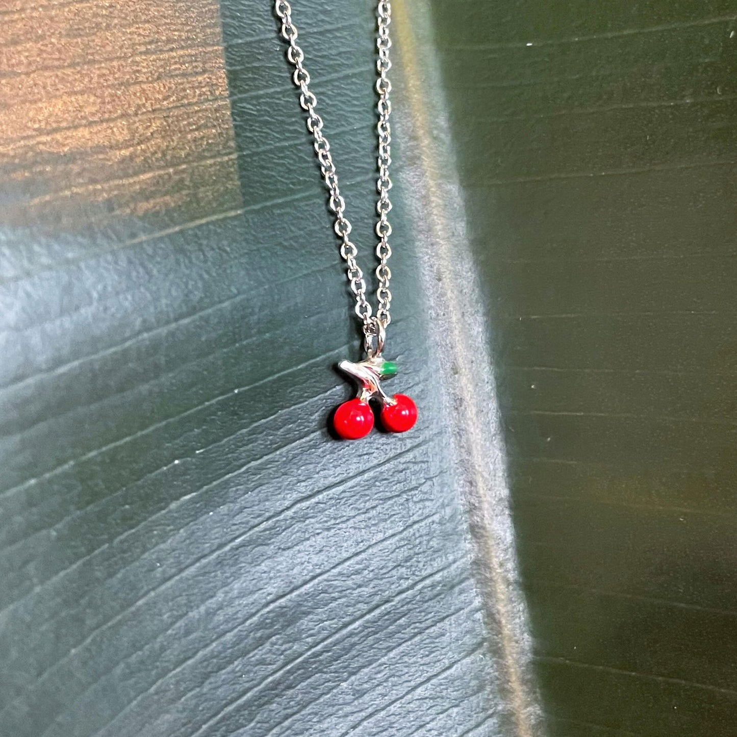 Photo of Cherry Necklace in a decorative scene, designed by , available at Plumb Gold & Plumb Silver