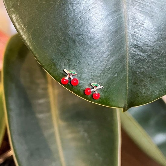 Photo of Cherry Stud Earrings in a decorative scene, designed by , available at Plumb Gold & Plumb Silver