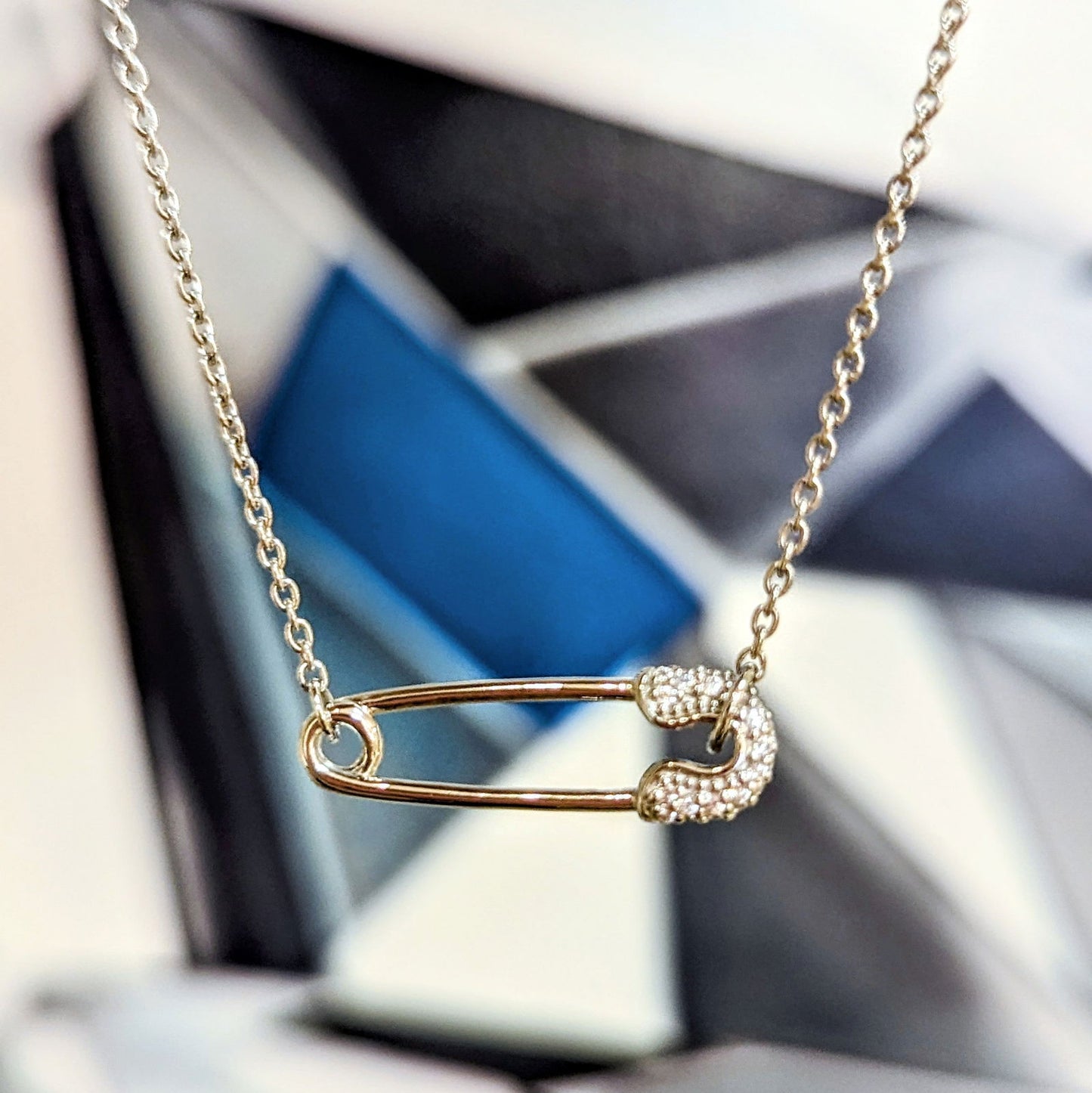 Photo of Chic Pin Necklace in a decorative scene, designed by , available at Plumb Gold & Plumb Silver