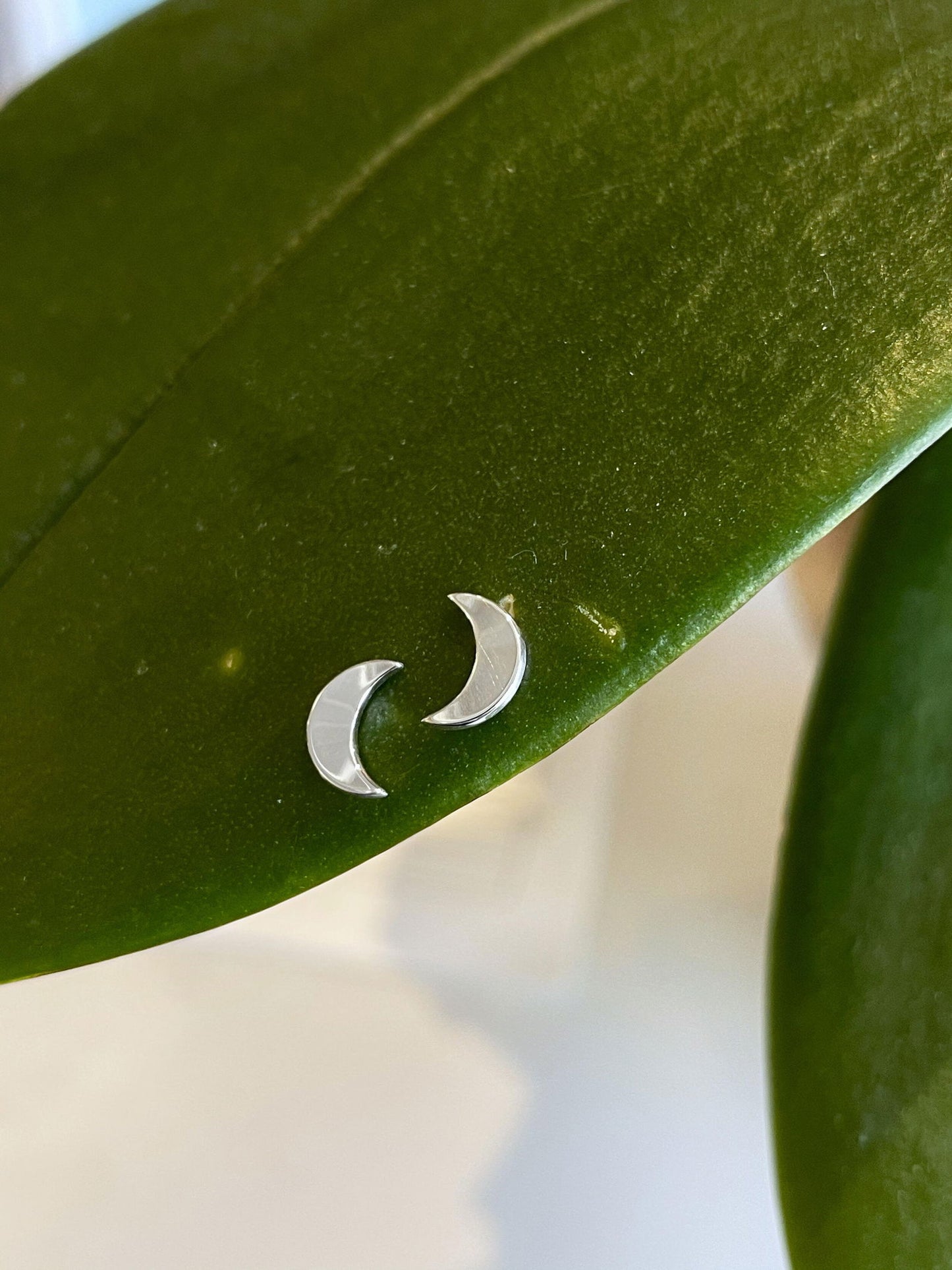 Photo of "Crescent Moon" Earrings in a decorative scene, designed by , available at Plumb Gold & Plumb Silver
