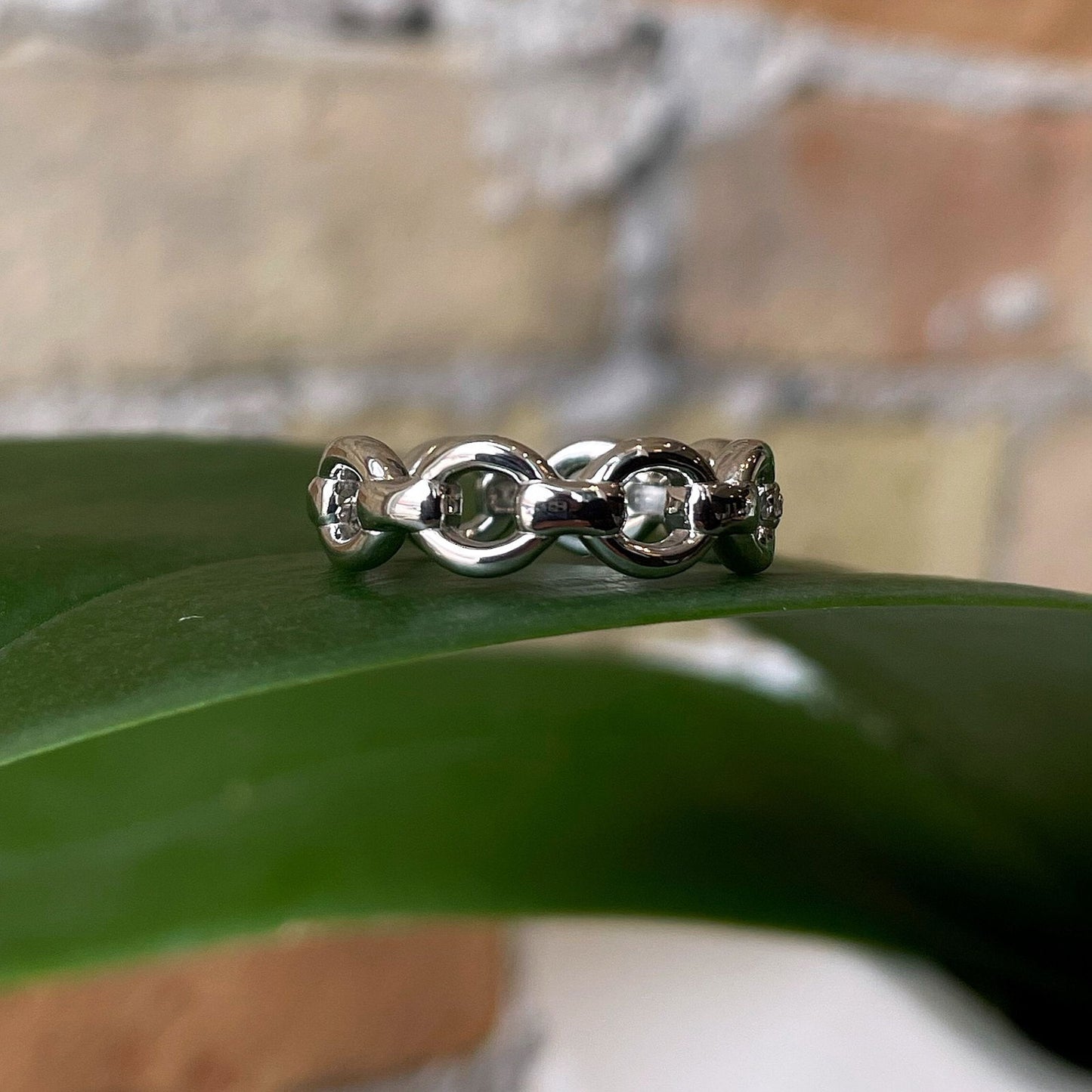 Photo of Cubic Zirconia Link Ring in a decorative scene, designed by , available at Plumb Gold & Plumb Silver