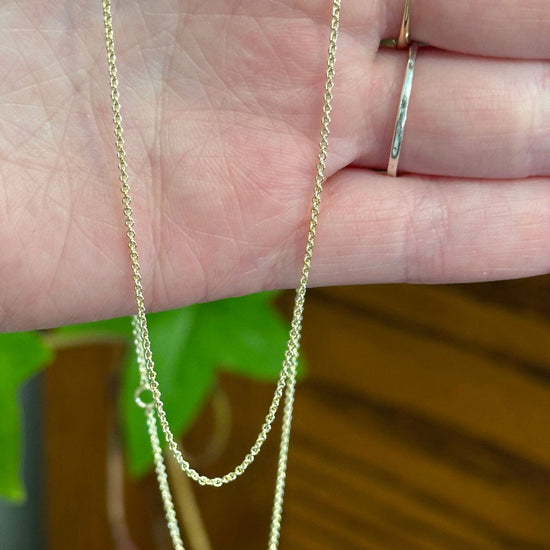Photo of Dainty Gold Cable Chain in a decorative scene, designed by , available at Plumb Gold & Plumb Silver