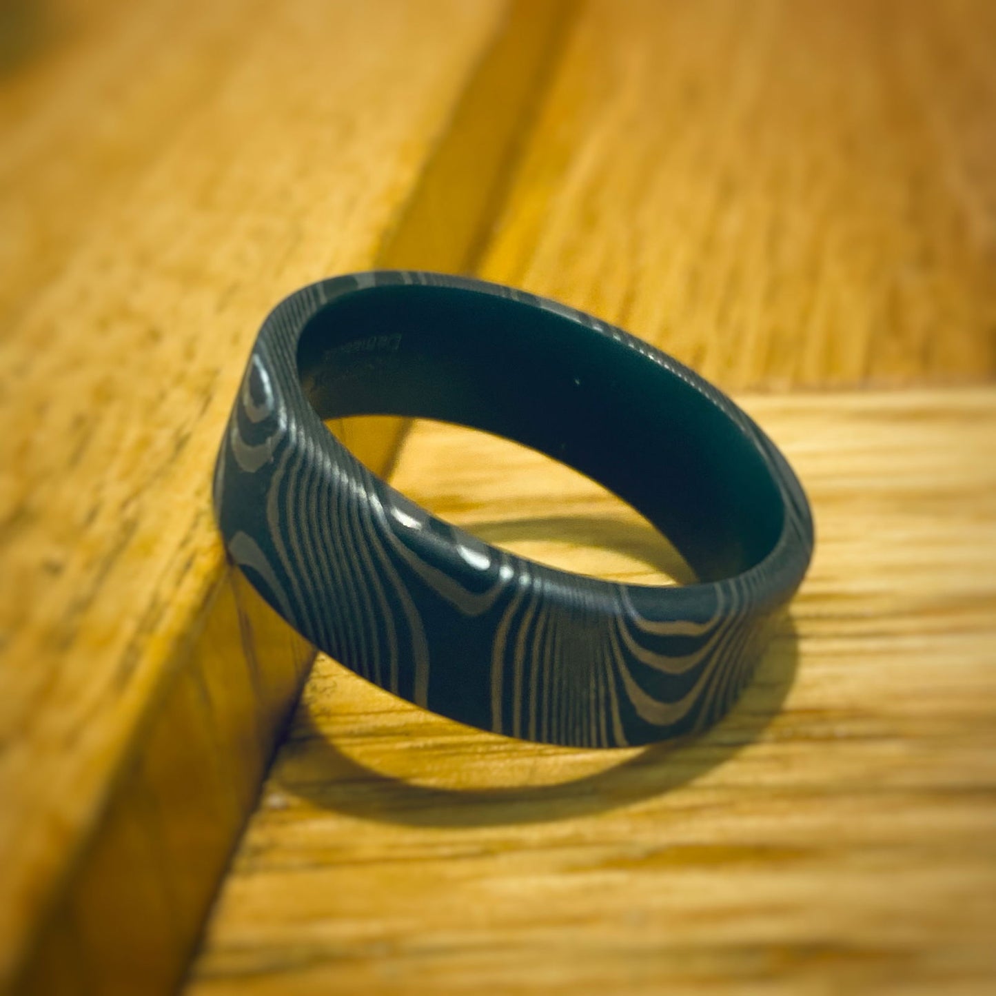 Photo of Damascus Flat Twist Band in a decorative scene, designed by -, available at Plumb Gold & Plumb Silver