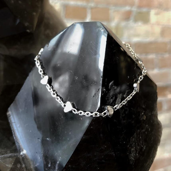 Photo of Diamond-Cut Heart Station Cable Bracelet in a decorative scene, designed by , available at Plumb Gold & Plumb Silver