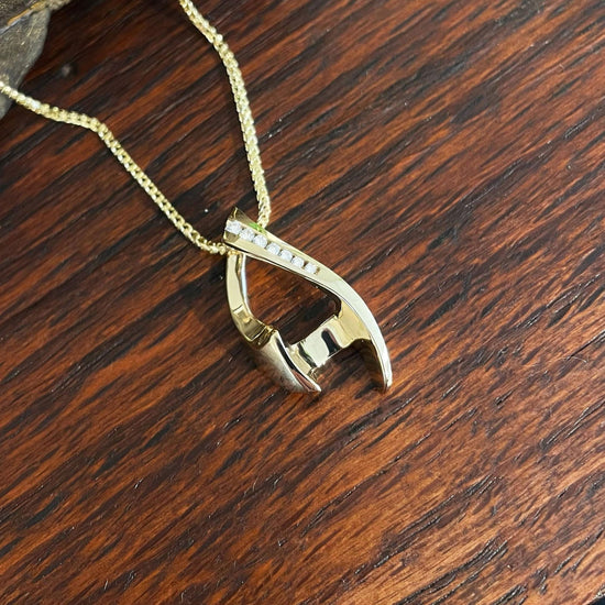 Photo of Diamond Chevron Pendant in a decorative scene, designed by , available at Plumb Gold & Plumb Silver
