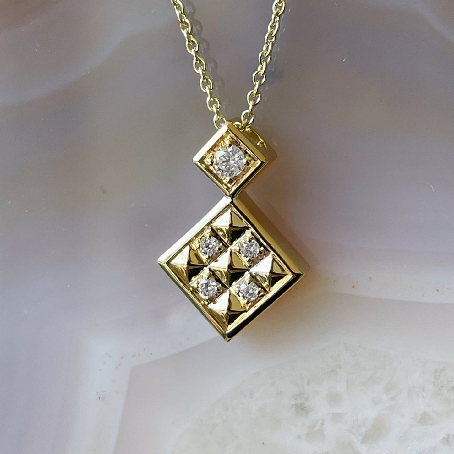 Photo of Diamond Geometric Necklace in a decorative scene, designed by , available at Plumb Gold & Plumb Silver