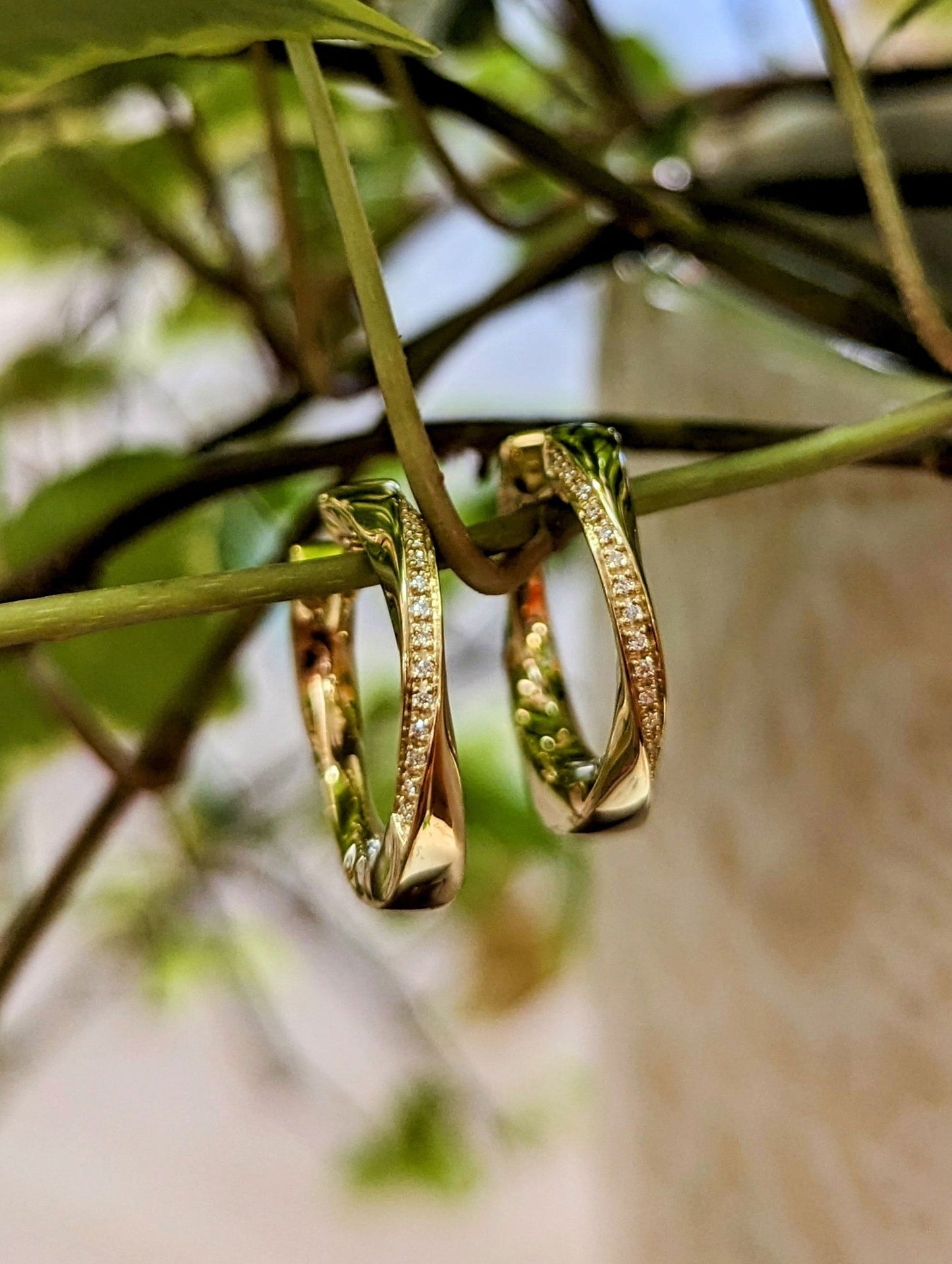 Photo of Diamond Twist Hinged Hoop in a decorative scene, designed by , available at Plumb Gold & Plumb Silver
