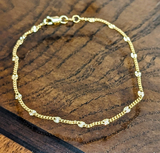 Photo of Disc station bracelet in a decorative scene, designed by , available at Plumb Gold & Plumb Silver