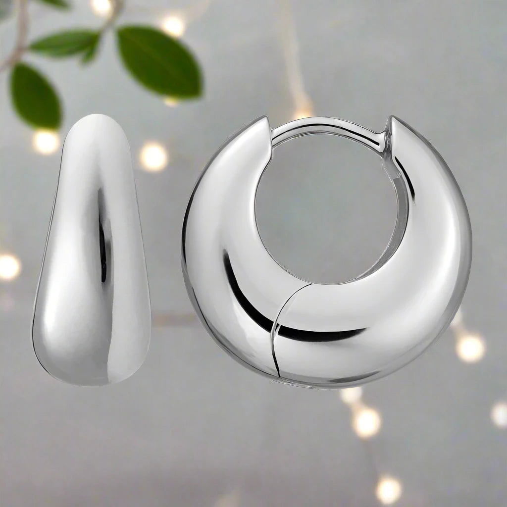Photo of Dome Tapered Huggie  Earrings in a decorative scene, designed by , available at Plumb Gold & Plumb Silver