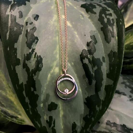 Photo of Double Circle Pendant with Diamond Accents in a decorative scene, designed by , available at Plumb Gold & Plumb Silver
