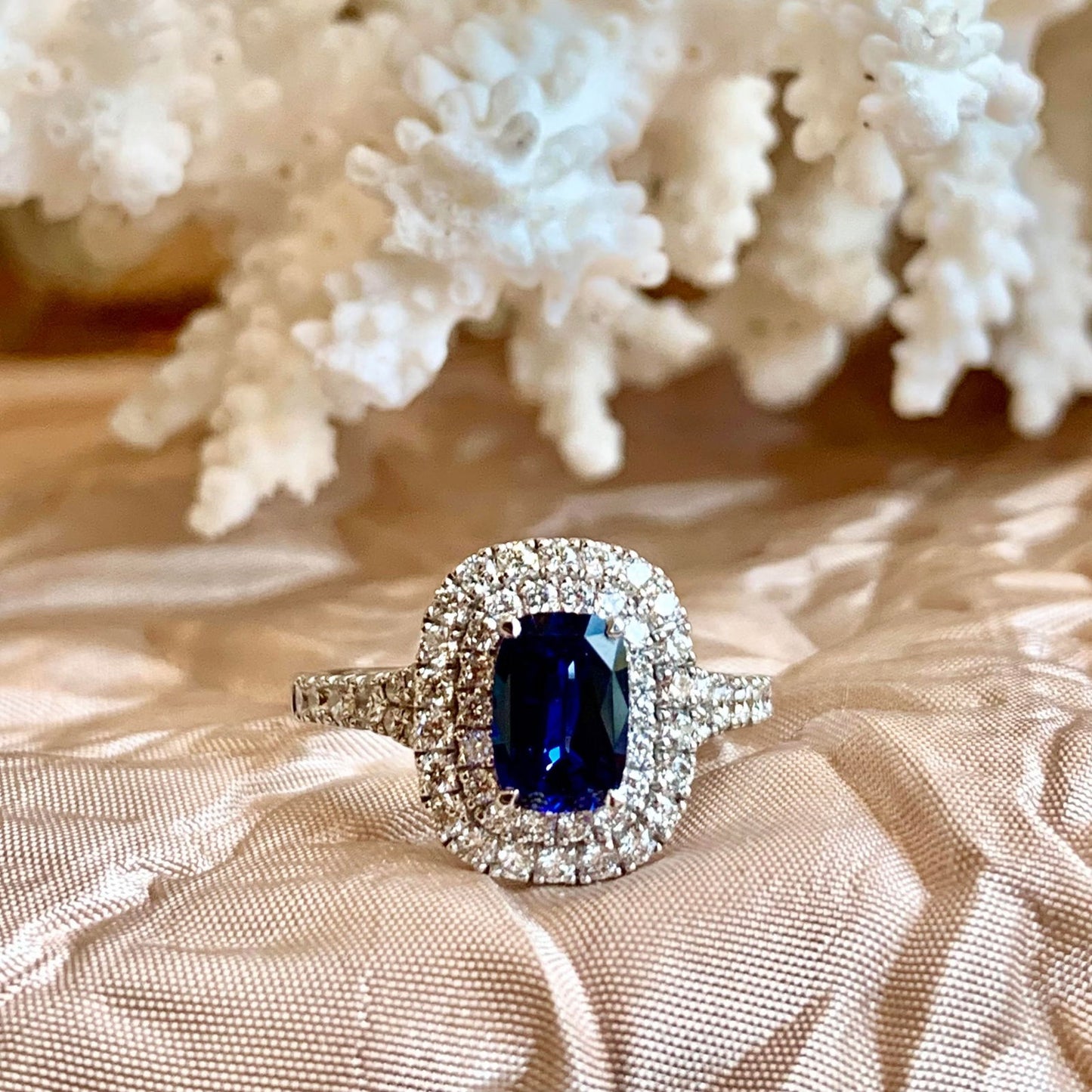 Photo of Double Halo Sapphire Ring in a decorative scene, designed by , available at Plumb Gold & Plumb Silver
