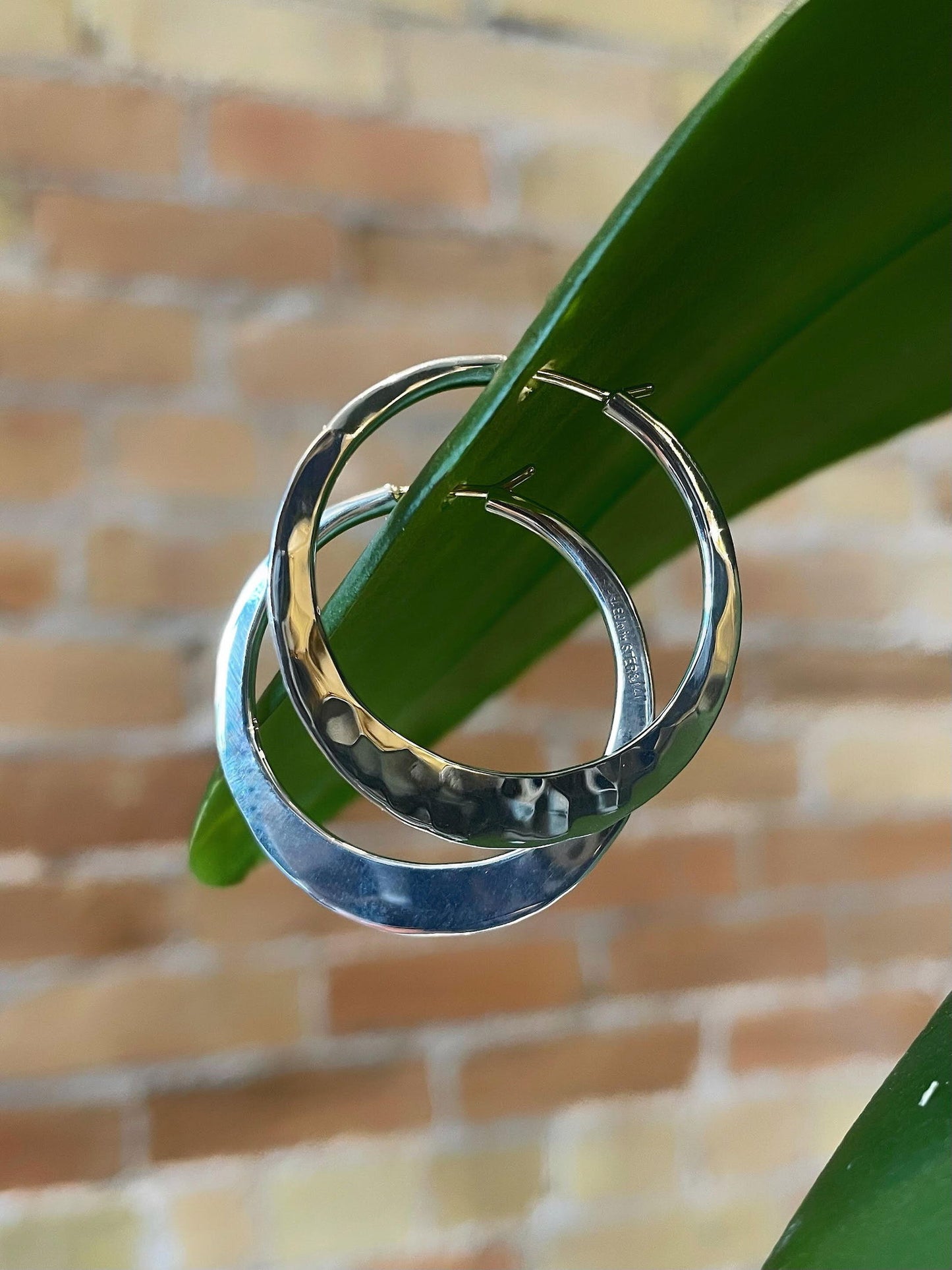Photo of EL Design Large "Hammered" Flat Hoop Earrings in a decorative scene, designed by , available at Plumb Gold & Plumb Silver
