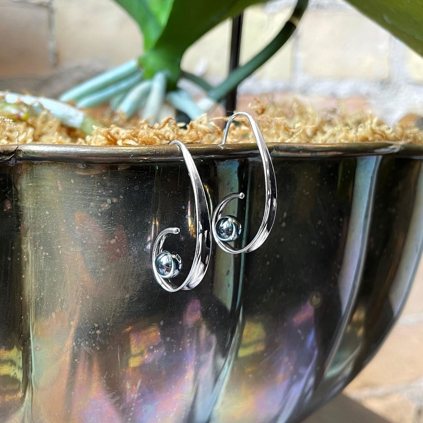 Photo of EL Designs "Crosswind" Hematite Earrings in a decorative scene, designed by , available at Plumb Gold & Plumb Silver