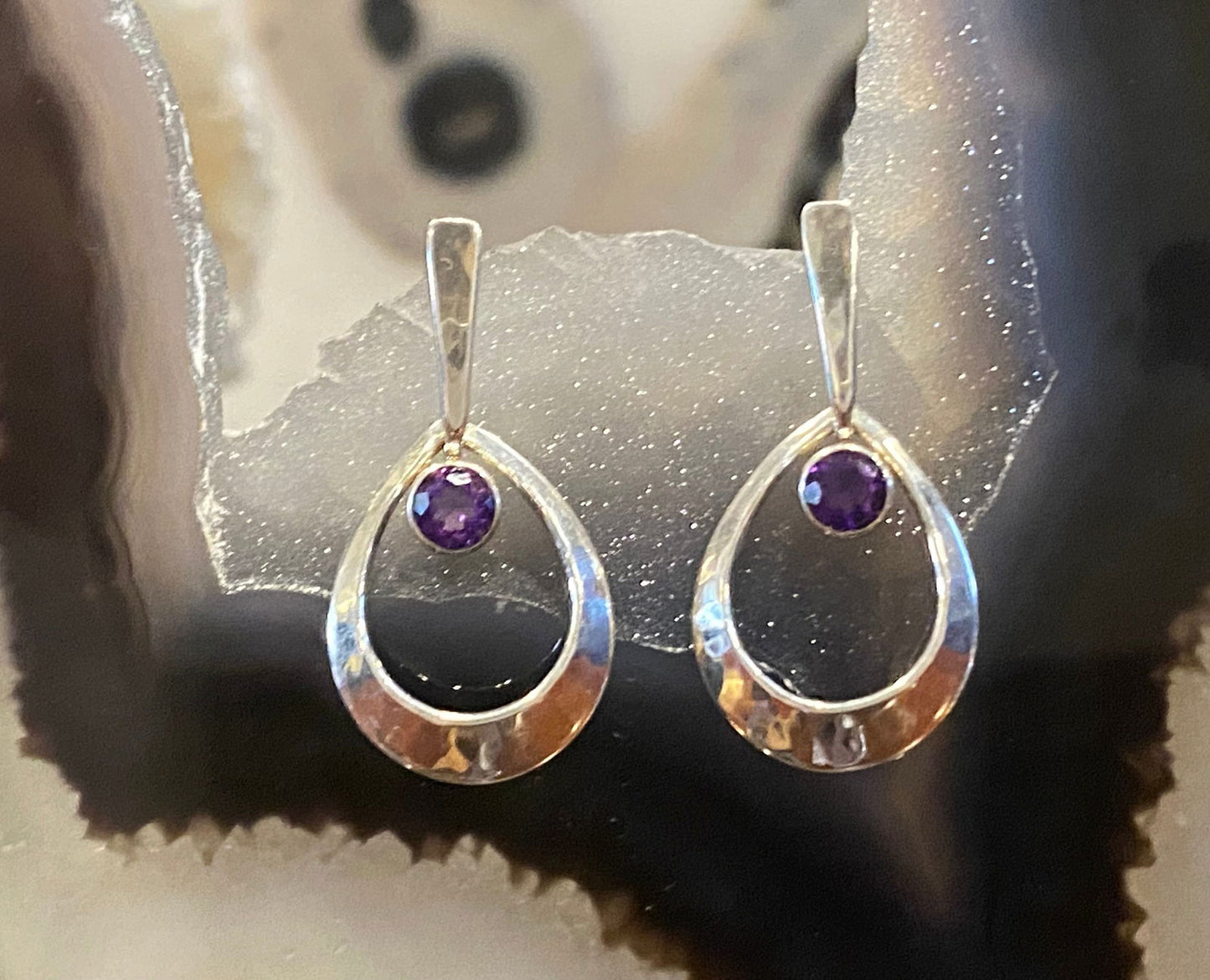 Earrings resting in a banded geode display, available at plumb silver jewelry store