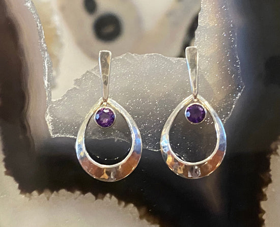 Earrings resting in a banded geode display, available at plumb silver jewelry store