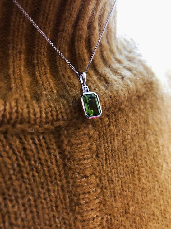 Photo of Emerald-Cut Peridot and Diamond Pendant in a decorative scene, designed by , available at Plumb Gold & Plumb Silver