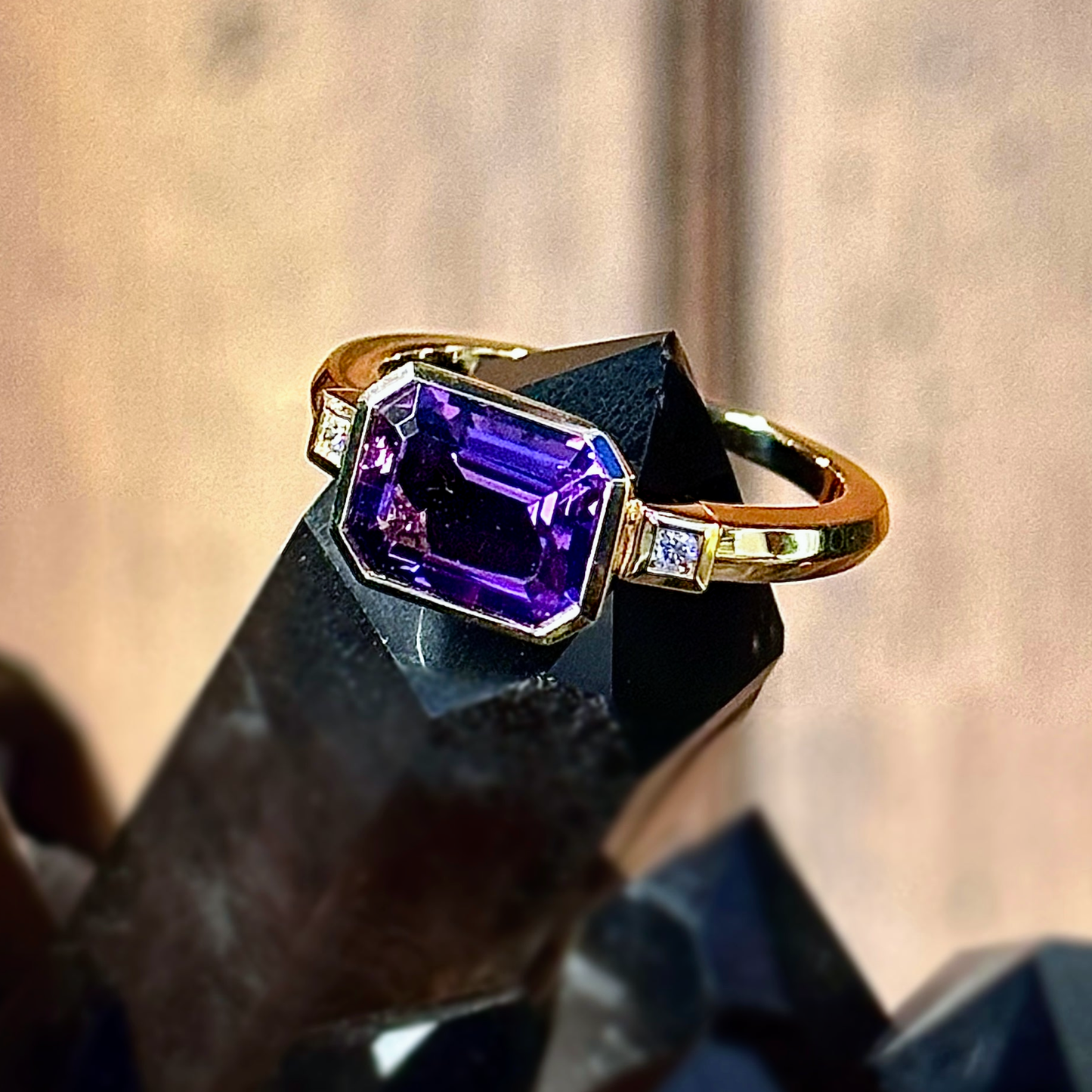 Photo of Emerald Cut Amethyst and Diamond Ring in a decorative scene, designed by , available at Plumb Gold & Plumb Silver