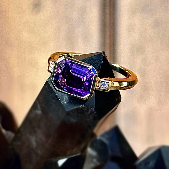 Photo of Emerald Cut Amethyst and Diamond Ring in a decorative scene, designed by , available at Plumb Gold & Plumb Silver