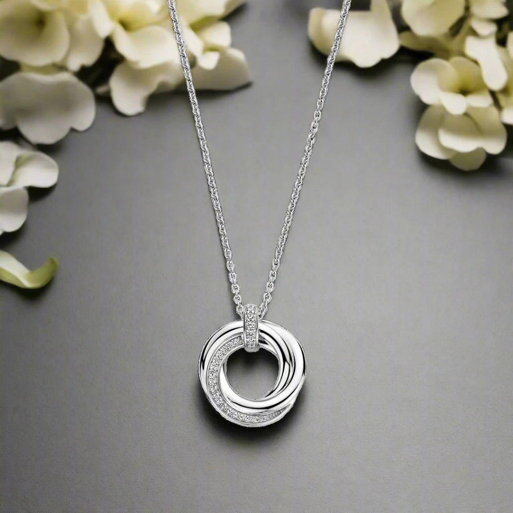 Photo of Entwined Circles Necklace in a decorative scene, designed by -, available at Plumb Gold & Plumb Silver