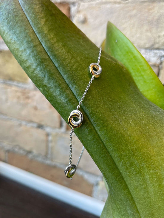 Photo of Entwined Circles Station Bracelet in a decorative scene, designed by , available at Plumb Gold & Plumb Silver