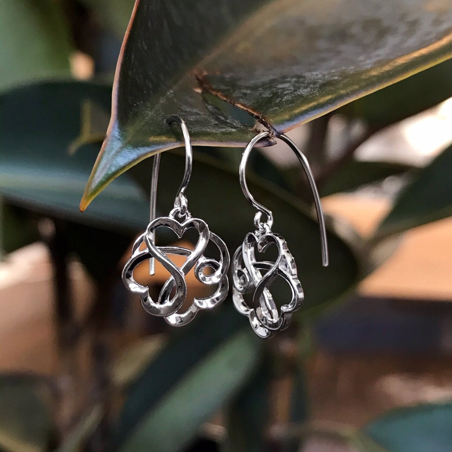 Photo of Entwined Hearts Earrings in a decorative scene, designed by , available at Plumb Gold & Plumb Silver