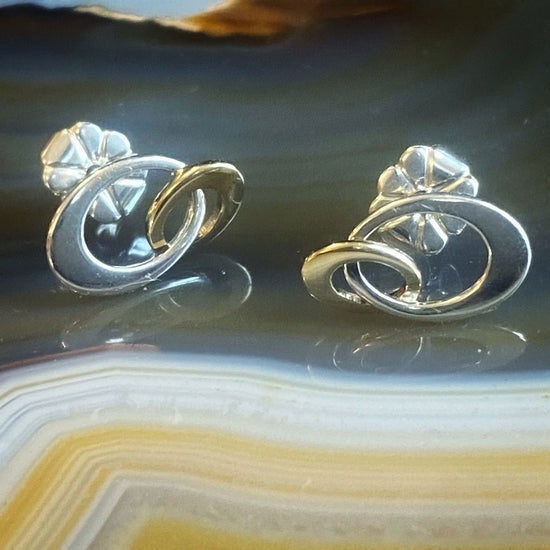 Photo of Entwined Mini Earrings in a decorative scene, designed by , available at Plumb Gold & Plumb Silver
